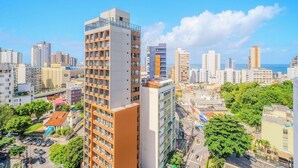 A high-rise building with multiple floors, surrounded by other buildings and greenery. - Modern and Complete Apartments 500m from Barra Beach in Salvador – ZNB (Salvador)