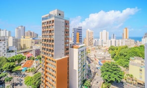 Un edificio alto con diversi piani, circondato da altri edifici e vegetazione.