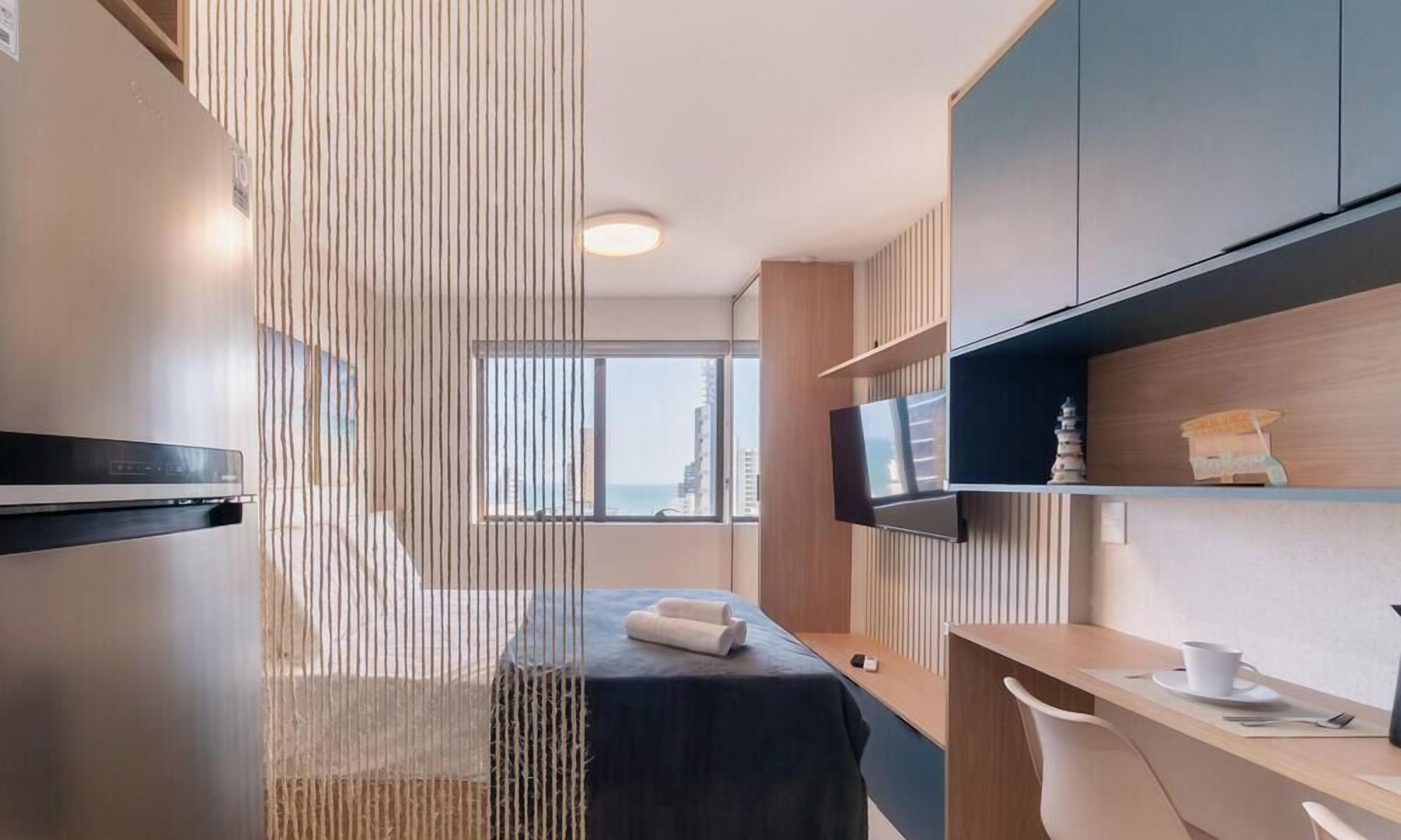 Una camera d'hotel moderna con un letto, una scrivania, una televisione e vista sulla città.