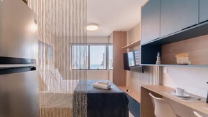 A modern hotel room with a bed, a desk, a television, and a view of the city. - Modern and Complete Apartments 500m from Barra Beach in Salvador – ZNB (Salvador)