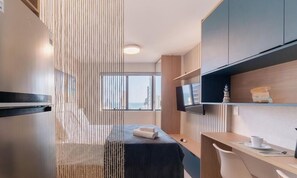 Une chambre d’hôtel moderne équipée d’un lit, d’un bureau, d’une télévision et offrant une vue sur la ville.