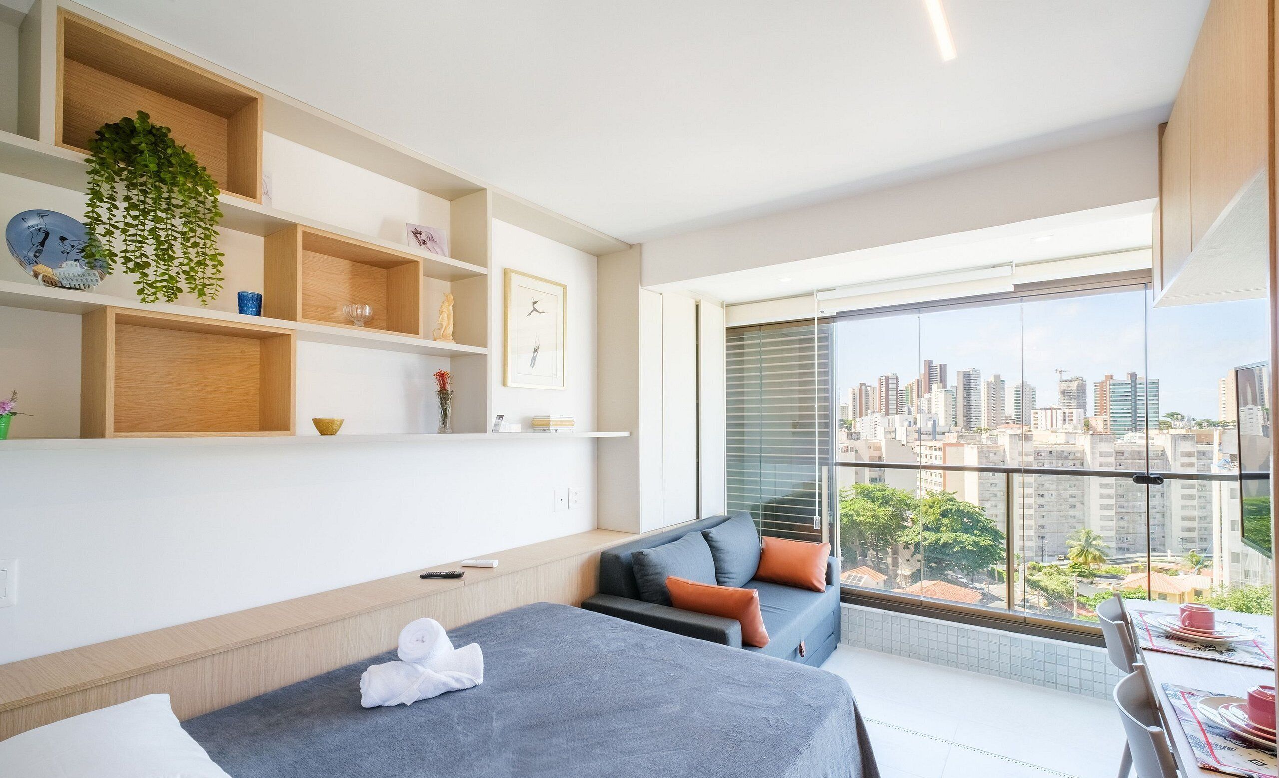 Una camera d'albergo moderna con un balcone, un divano, un letto e una mensola a parete con oggetti decorativi.