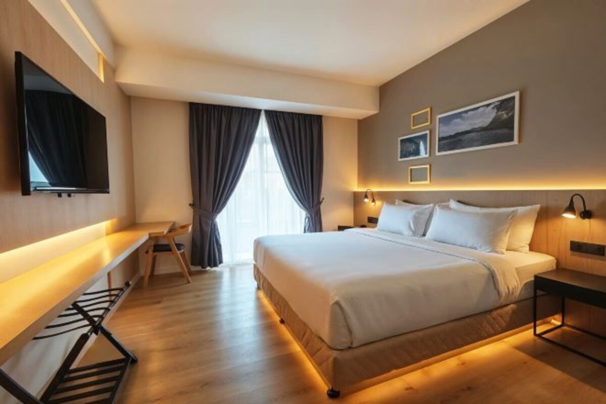 Quarto de hotel moderno com uma cama grande, uma escrivaninha, televisão de tela plana e obras de arte nas paredes.