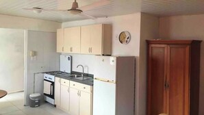 Una cocina compacta con estufa, lavamanos y armarios.