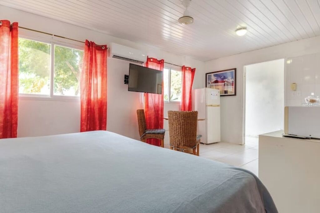 A bedroom with a bed, a TV, a chair, and a desk.