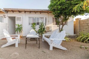Eine Terrasse mit weißen Adirondack-Stühlen, einem Tisch und Topfpflanzen.
