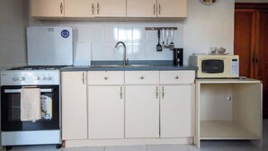 Una cocina compacta con estufa, horno, pileta y microondas.