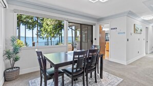 Een eethoek met een tafel en stoelen, met uitzicht op de zee, en een moderne plafondlamp.