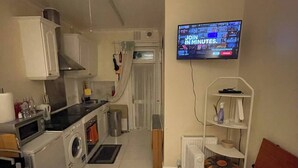 Une chambre d’hôtel compacte comprenant un coin cuisine, un lit, une télévision et un petit espace salon.