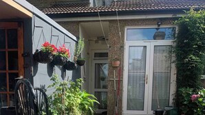 Un espace patio aménagé avec une chaise, des plantes en pot et une porte donnant sur une entrée abritée.