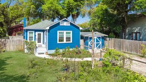 A blue house with a fenced yard, a small shed, and a wooden fence.