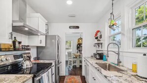 A modern kitchen with white cabinetry, stainless steel appliances, and a marble countertop.