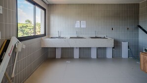 A bathroom with a large window, two sinks, and tiled walls. -  Apartamentos em Prédio c/Academia na Ondina-SSA-HOA (Salvador)