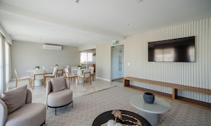 A modern hotel lobby with a dining area, a seating area with a TV, and a reception desk. -  Apartamentos em Prédio c/Academia na Ondina-SSA-HOA (Salvador)