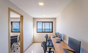 A conference room with a view of the sea, equipped with a long table, chairs, and computers. -  Apartamentos em Prédio c/Academia na Ondina-SSA-HOA (Salvador)