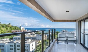 A balcony with a view of the ocean and cityscape. -  Apartamentos em Prédio c/Academia na Ondina-SSA-HOA (Salvador)
