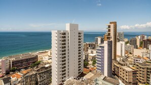 Un edificio de gran altura con varios pisos, una playa al fondo y un cielo despejado.