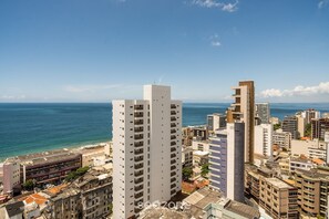 A high-rise building with multiple floors, a beach in the background, and a clear sky.