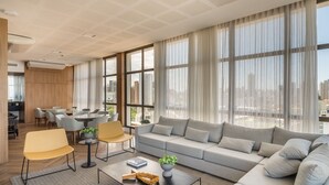 Una sala moderna con un sofá grande de color gris, una mesa de centro con una planta, y un comedor con sillas y una mesa.