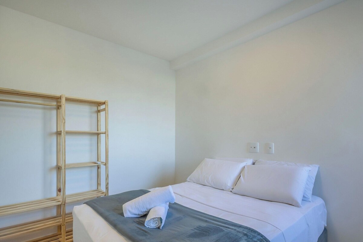 A simple, clean room with a bed, a wooden wardrobe, and a wall socket.