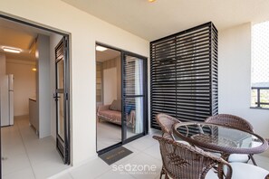 Un interior moderno con una puerta de vidrio que da a un dormitorio, muebles de mimbre y un panel divisor de listones negros.