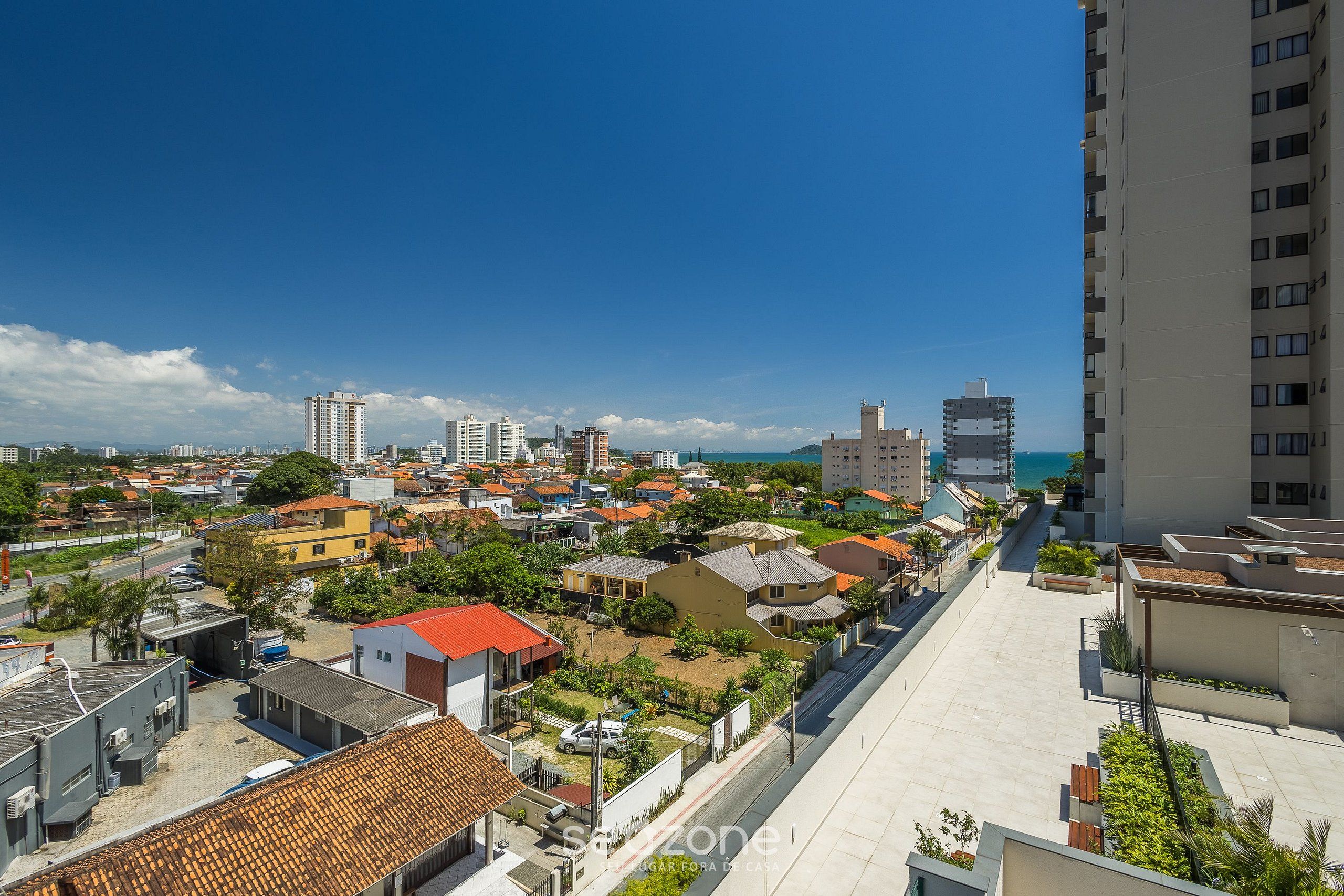 A residential area with a mix of buildings, including a tall apartment building and smaller houses, with a clear sky above.