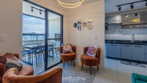 Un appartement moderne doté d’un balcon, d’une cuisine et d’un coin salon avec deux fauteuils.