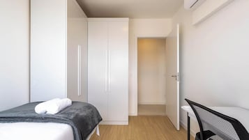A bedroom with a bed, a desk, and a wardrobe.