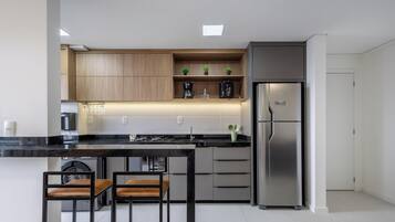A modern kitchen with a stainless steel refrigerator, wooden cabinets, and a black countertop.