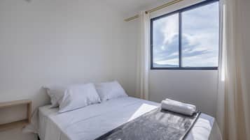 Un dormitorio con cama, ventana y vista al cielo.