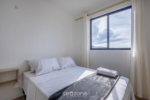 Un dormitorio con cama, ventana y vista al cielo.