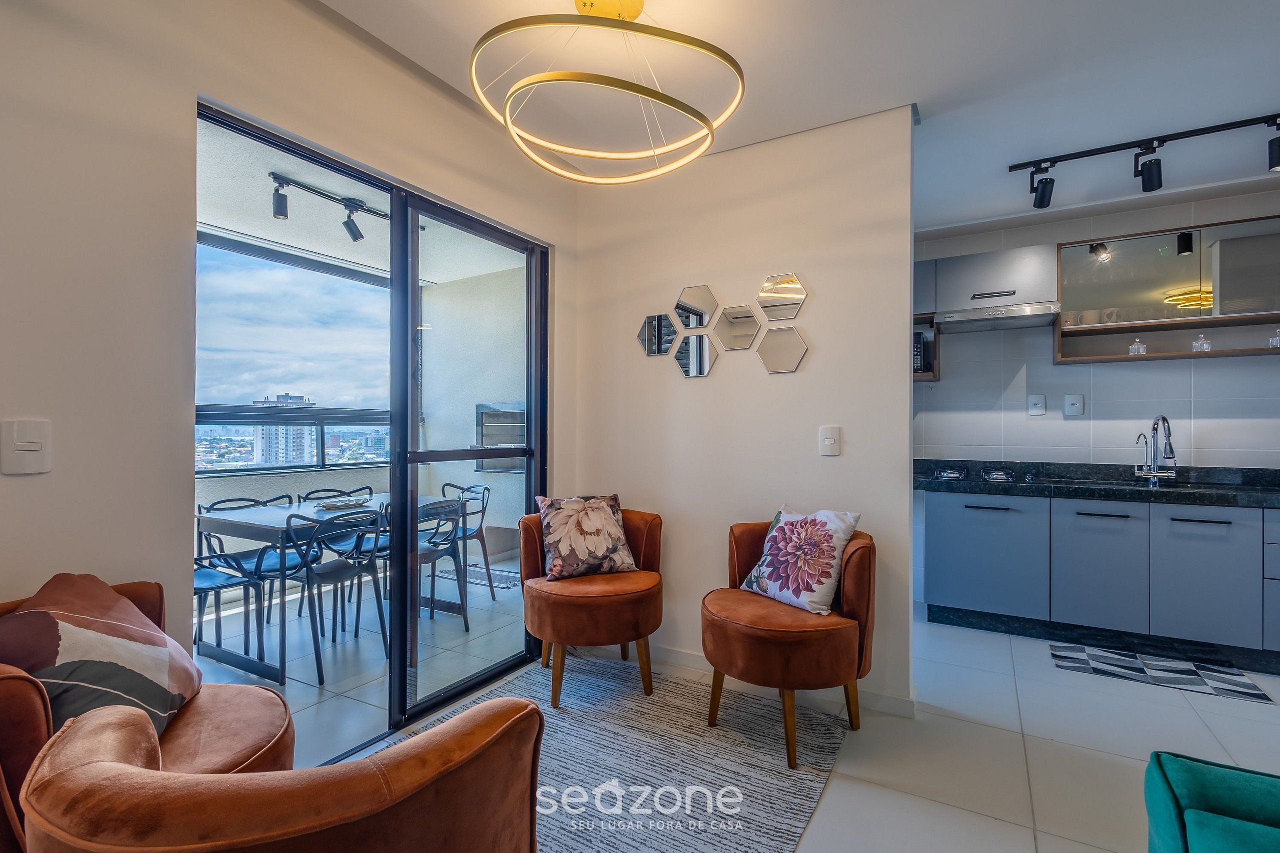 Un apartamento moderno con balcón, cocina y zona de estar con dos sillas.