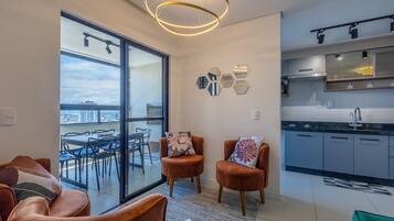Un apartamento moderno con balcón, cocina y zona de estar con dos sillas.