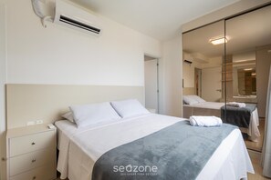 Una habitación de hotel con cama, mesita de noche y espejo.