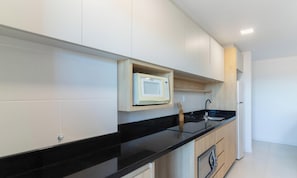 Een moderne keuken met witte kasten, een zwart aanrecht en een ingebouwde magnetron.