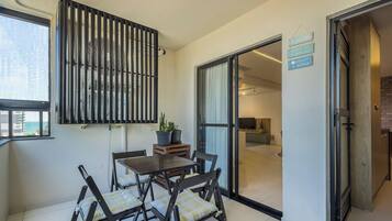 A balcony with a view of the sea, a dining area with a table and chairs, and a sliding glass door leading to a kitchen.
