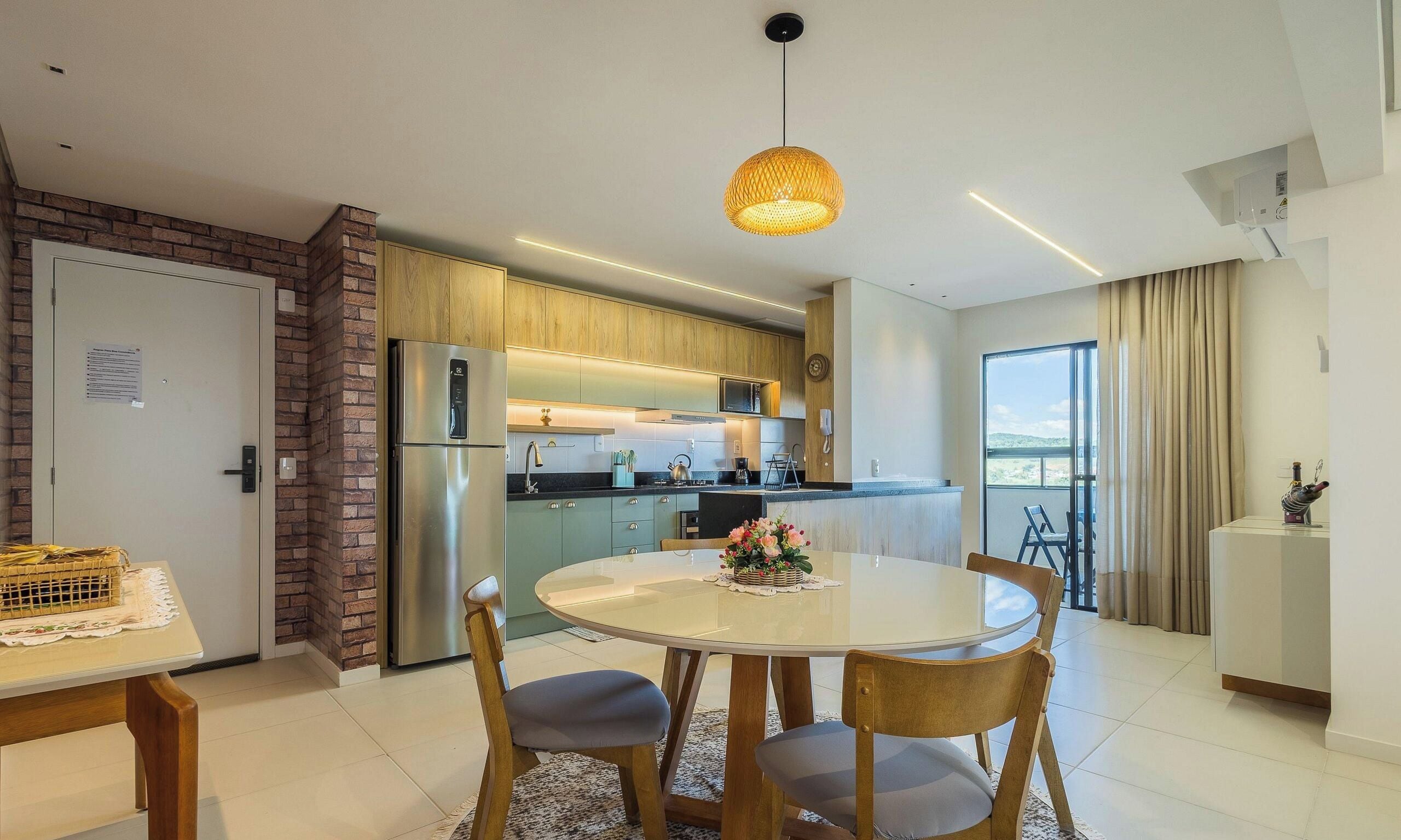 A modern kitchen with a built-in refrigerator, wooden cabinets, and a round dining table with chairs.