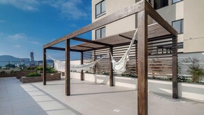 Une terrasse sur le toit, agrémentée d’une pergola en bois, de deux hamacs blancs et offrant une vue sur le paysage urbain.