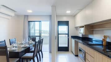 A modern kitchen with a dining area, a black countertop, and a view through the door.
