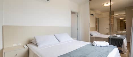 Una habitación de hotel con cama, mesita de noche y espejo.