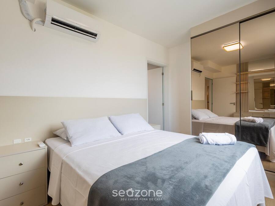 Una habitación de hotel con cama, mesita de noche y espejo.