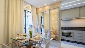 Un espace repas moderne avec une table en verre, des chaises blanches et un vase de fleurs.