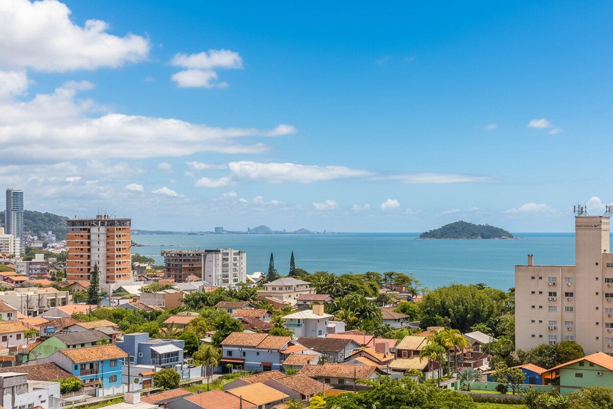 Un paysage urbain côtier avec des immeubles résidentiels, une tour imposante et une île au loin.