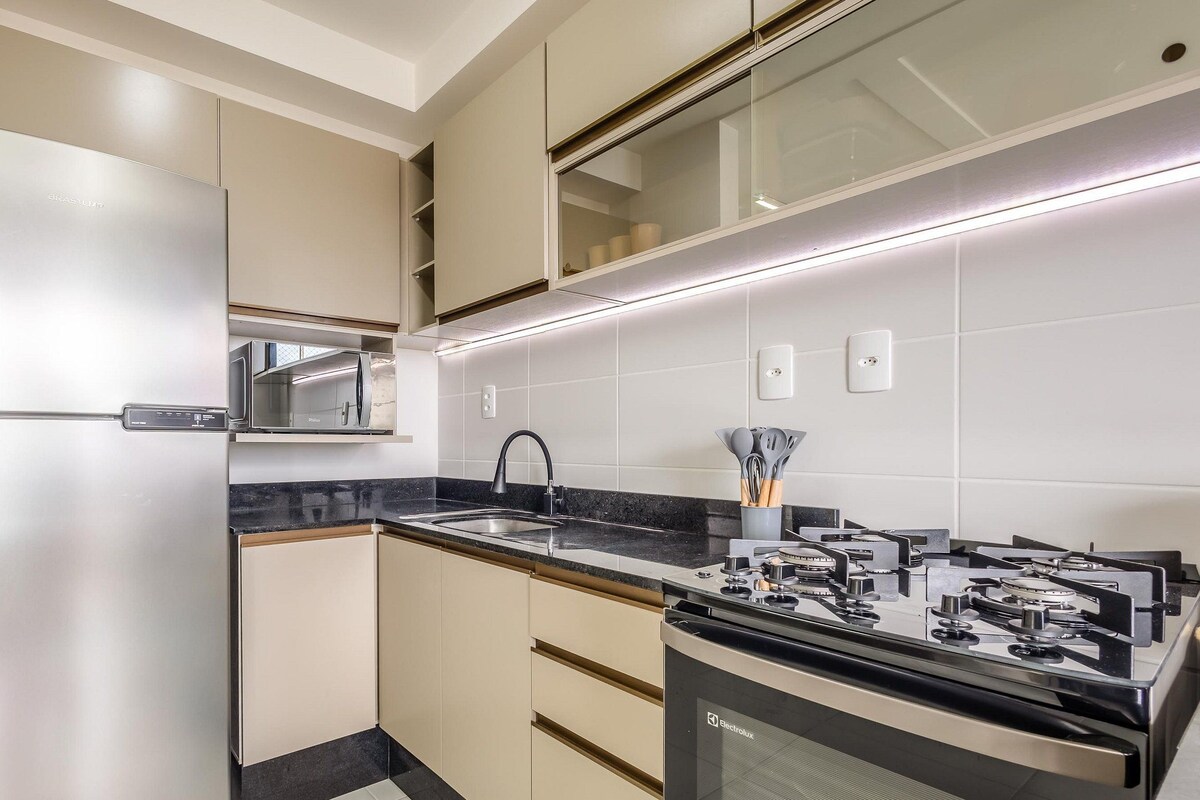 A modern kitchen with a stainless steel refrigerator, a built-in microwave, a gas stove, and a sink.