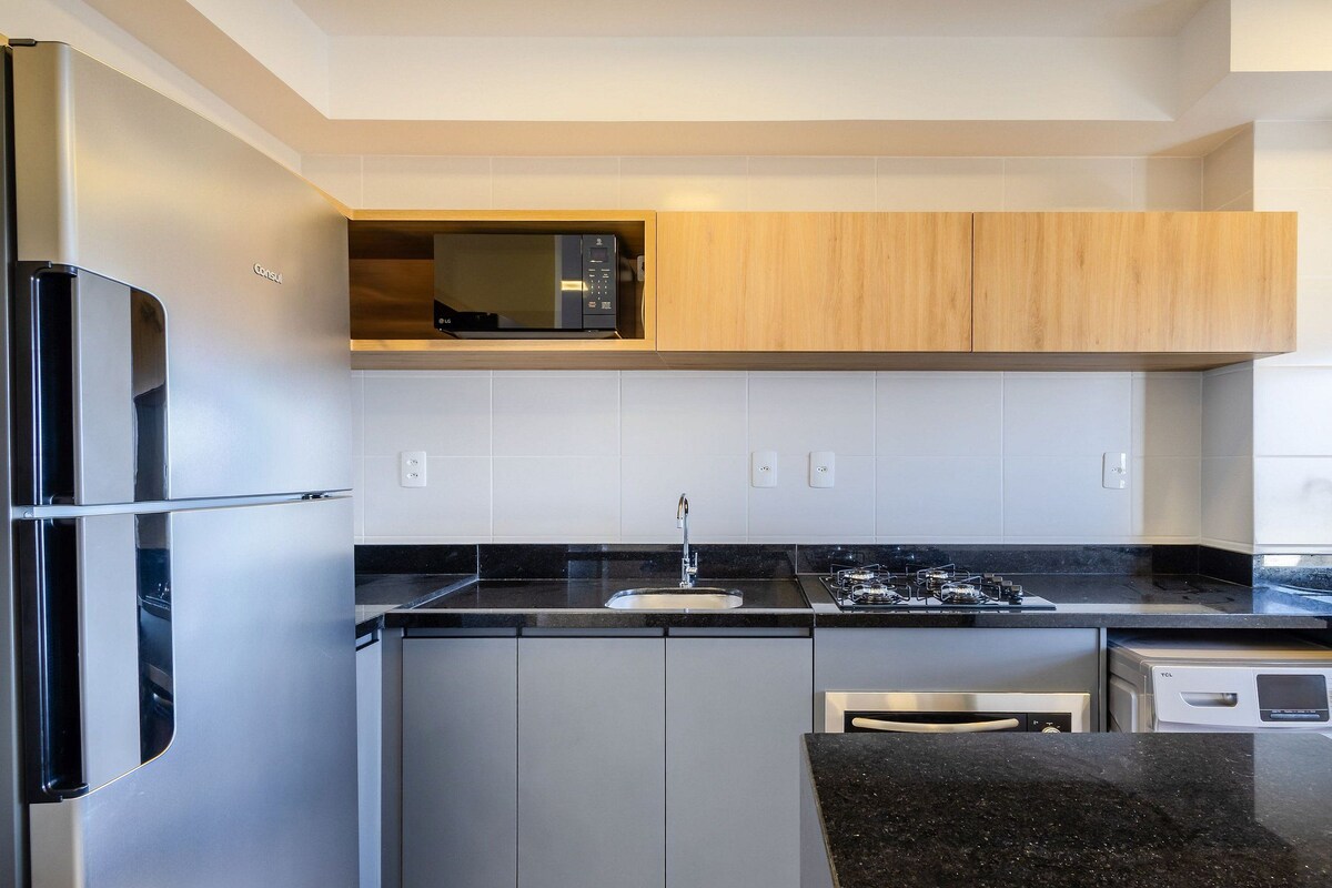 A modern kitchen with stainless steel appliances, wooden cabinets, and a black countertop.