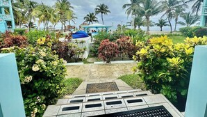 Un sendero en un resort con palmeras, un edificio azul y vistas al mar.