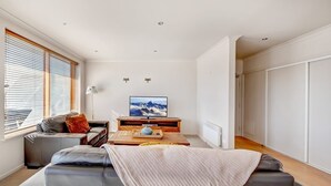 A modern living room with a sofa, a coffee table, a TV, and a window with blinds. - Schnapps 3 - Mt Hotham (Hotham Heights)