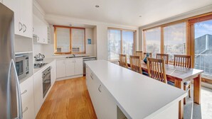 A modern kitchen with white cabinetry, wooden flooring, and a central island. - Schnapps 3 - Mt Hotham (Hotham Heights)