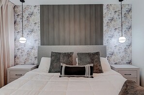 A bedroom with a large bed, two bedside tables, a headboard, and floral wallpaper. - 9140 Mario Game Room, Theater & Pool! Solara 6BR (Kissimmee)