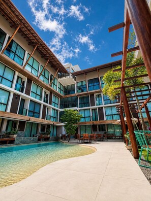 A hotel courtyard with a swimming pool, outdoor seating, and a multi-story building with large windows. - Sunny Hall - V.S.H. (Ipojuca)